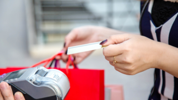 A woman pays for purchases using a tap machine